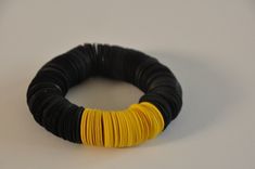 a black and yellow bracelet on a white surface