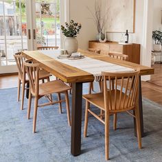 a dining room table with chairs and a rug on the floor in front of it