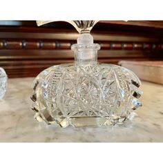 a clear glass bottle sitting on top of a marble table next to two crystal vases