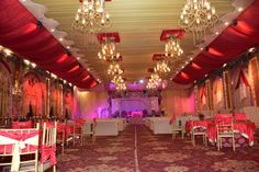 an elaborately decorated banquet hall with chandeliers and red drapes on the ceiling