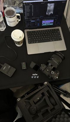 an open laptop computer sitting on top of a table next to a camera and other items