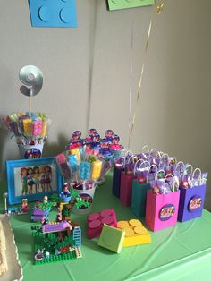 a table topped with legos and bags filled with candy bar items on top of a green table cloth