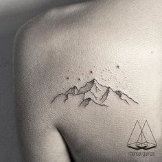 the back of a woman's shoulder with mountains and stars on it