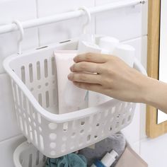 a person's hand holding a soap and lotion in a white laundry basket