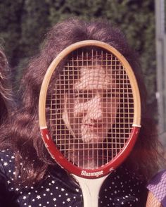 a woman holding a tennis racquet in front of her face with the net covering it's face