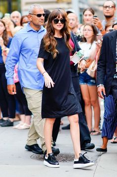 a woman is walking down the street with her hand in her pocket and people behind her