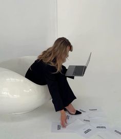 a woman is sitting on the floor with her laptop in front of some sheets of paper