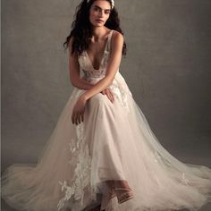 a woman in a wedding dress sitting on a stool