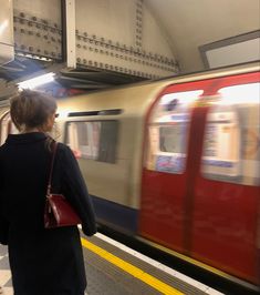 a woman is waiting for the train to arrive at the station as it passes by