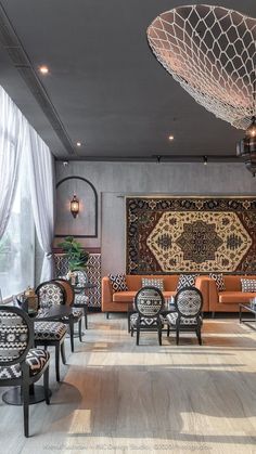 a living room filled with furniture next to a large rug on the wall and windows