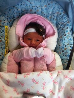 a small child is sitting in a stroller with pink and white blankets on it