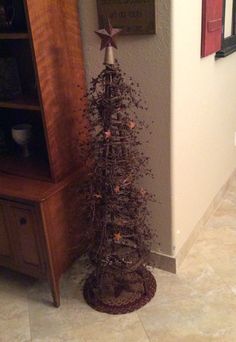 a small christmas tree sitting in the corner of a room next to a book shelf