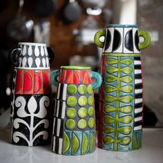 three colorful vases sitting on top of a counter