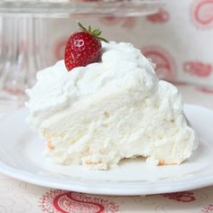 a piece of cake with whipped cream and a strawberry on top sits on a plate