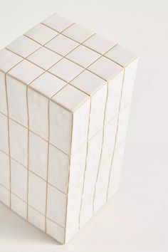 a white cube with gold lines on the top and bottom, sitting in front of a white background