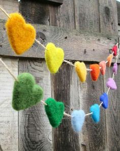 felt hearts are hung on a clothes line with pegs to hang them from a wooden fence