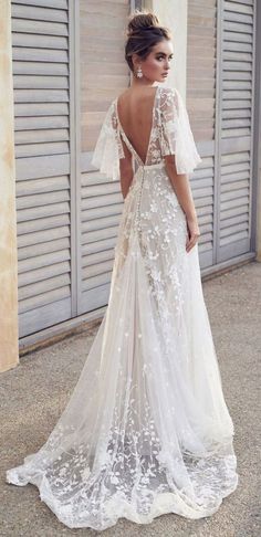 a woman in a white wedding dress is standing outside with her back to the camera