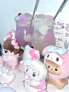 there are many stuffed animals next to each other on the table with cups and drinks