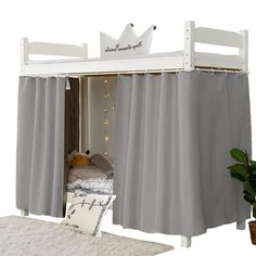 a white bunk bed with curtains on the top and bottom, next to a potted plant