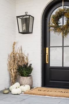 the front door is decorated for fall with pumpkins and gourds