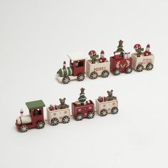 a group of toy trains with christmas trees on the front and side cars in red, white and green