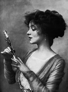 an old black and white photo of a woman holding a pipe in her hands,