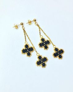 four - leaf clover earrings in gold and black seed bead, set against a white background