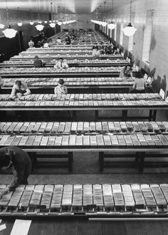 an old black and white photo of people working in a factory with lots of trays