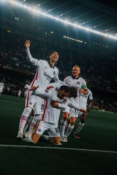 the soccer team is celebrating their goal in front of an audience at night time,