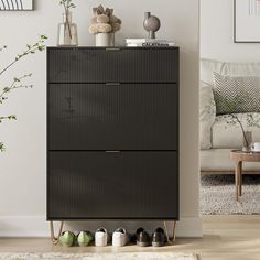 a living room with a white couch and some shoes on the floor in front of a black cabinet