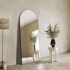 a mirror sitting on top of a white table next to a vase filled with plants