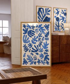 two blue and white paintings on the wall next to a wooden table in a room