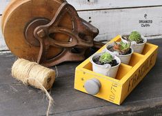 a planter with succulents in it next to a wooden spool