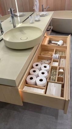 an open drawer in the middle of a bathroom counter with toilet paper and other items