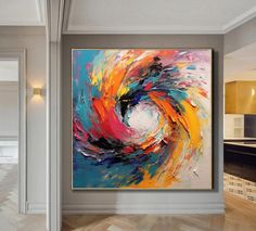 an abstract painting hangs on the wall above a wooden floor in front of a doorway