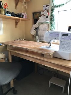 a sewing machine sitting on top of a wooden table next to a chair and window