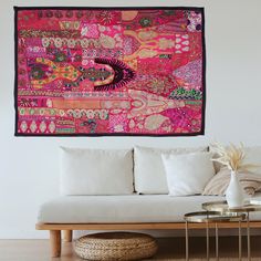 a living room with a couch, table and large tapestry hanging on the wall above it