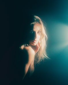 a woman is posing in the dark with her hand on her face