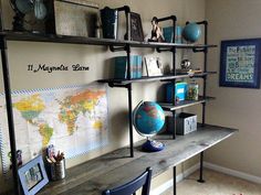 a desk with some books and pictures on the wall next to it, in front of a map