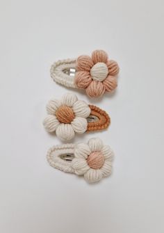 three crocheted hair clips with flowers on each one and two pins in the middle