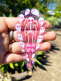 a hand holding a pink sticker with skulls on it