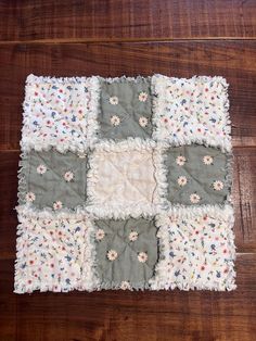 a piece of cloth with flowers on it sitting on a wooden floor next to a pair of scissors