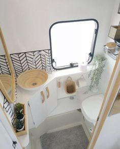 the interior of a small bathroom with a toilet, sink and mirror on the wall