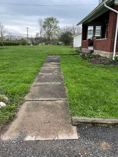 a sidewalk in front of a house with grass on both sides and an open door