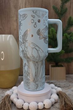 a white coffee cup sitting on top of a table next to a vase and beads