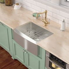 a kitchen with green cabinets and stainless steel sink