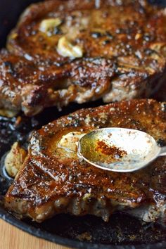 two steaks being cooked in a skillet with a spoon