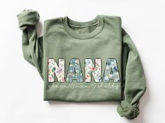 ♥ The perfect gift for Nana, featuring a super cute floral Nana design with personalized grandkids' names printed on a cozy crewneck sweatshirt, sure to warm her heart for Mother's Day, her birthday, Christmas, or all throughout the year! ♥ About Printing/Garment: All of our apparel is printed using DTG printing in which the design is printed directly onto the garment which reduces cracking and peeling over time when cared for properly.  Graphics are NOT vinyl. :) This heavy blend crewneck sweatshirt features a cozy, brushed interior in a variety of colors for maximum comfort & style. It is made of a cotton/polyester blend featuring a classic unisex fit.  ♥ Sizing Info: This sweatshirt is unisex sizing with a classic fit.   *If you would like to achieve a more oversized look, I recommend s Nana Sweatshirt Ideas, Personalized Cotton Sweatshirt For Mother's Day, Mother's Day Sweatshirt With Name Print And Crew Neck, Nana Sweater, Personalized Crew Neck T-shirt For Mother's Day, Nana Christmas Gifts, Nana Sweatshirt, Nana Shirts, Nana Gifts