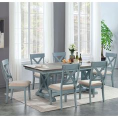 a dining room table with four chairs and a vase on the floor next to it