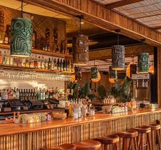 a bar with wooden stools and lots of bottles on the shelves in front of it